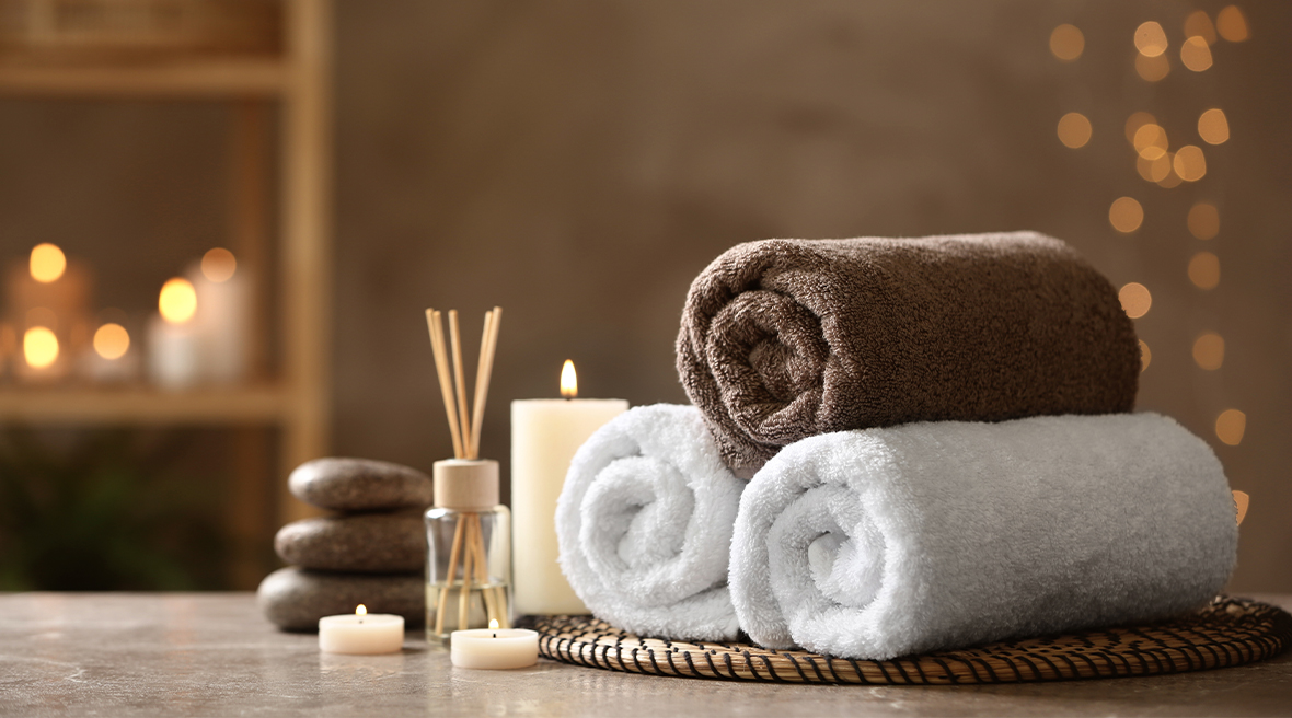 An arrangement of spa products – fluffy towls, candles, scent diffusers, stones